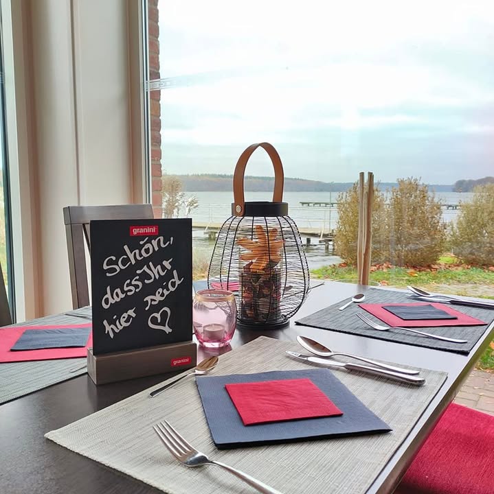Gedeckter Tisch am Panoramafenster mit Seeblick im Restaurant Haus am See